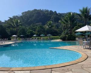 a large swimming pool with chairs and umbrellas at Apartamento em Resort Angra dos Reis in João Neiva
