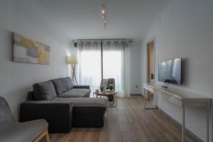 een woonkamer met een bank en een flatscreen-tv bij AZZ Sevilla Torre de la Plata Apartamentos in Sevilla