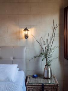 a vase with a plant on a table next to a bed at Casa Theano - Old Town in Rhodes Town
