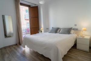 Un dormitorio con una gran cama blanca y una ventana en AZZ Sevilla Torre de la Plata Apartamentos, en Sevilla