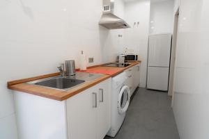 uma cozinha branca com um lavatório e um frigorífico em AZZ Sevilla Torre de la Plata Apartamentos em Sevilha