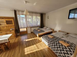 a bedroom with two beds and a desk and a window at Willa Strumyk in Zakopane