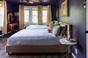 um quarto roxo com uma cama e uma mesa em Eden Brae: Historic Southern Gothic Mansion em Birmingham