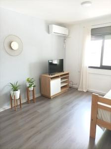 a white living room with a tv and a cabinet at Buenaventura Apartments Terrazas in Mendoza