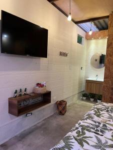 1 dormitorio con TV de pantalla plana en la pared en ADAMA BIOHOTEL, en Calima