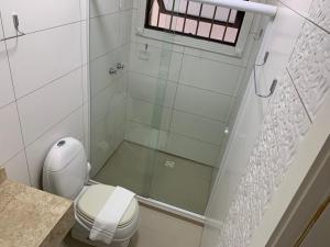 a white bathroom with a shower and a toilet at Pousada Azimute in Torres