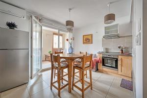 cocina y comedor con mesa y sillas en Îlot COQUELICOT - PARKING GRATUIT SECURISE - AC CLiM - ASCENSEUR - BALCON, en LʼIsle-sur-la-Sorgue