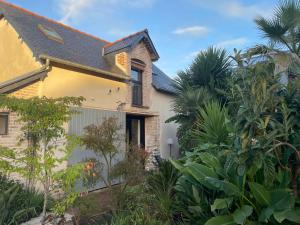 une maison avec des arbres et des plantes devant elle dans l'établissement La petite maison dans la jungle, à Chartres-de-Bretagne