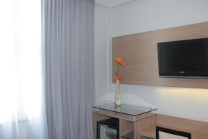 a room with a tv and a vase with flowers on a table at Hotel Atlântico Tower in Rio de Janeiro