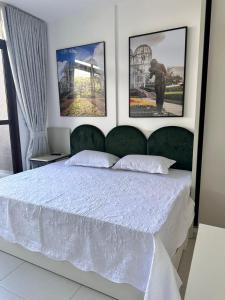 a bedroom with a white bed with three pictures on the wall at Estúdio Lindíssimo com Varanda! in Curitiba