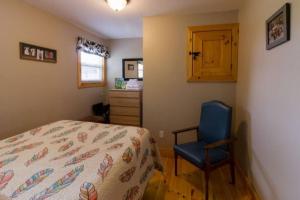 ein Schlafzimmer mit einem Bett und einem blauen Stuhl in der Unterkunft Steps to Lake on the Mountain - License ST-2020-0324 R1 in Picton