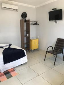 1 dormitorio con 1 cama, 1 silla y TV en Pousada Trilha do Sol, en Pirenópolis