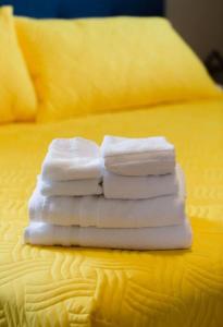 vier Handtücher auf einem gelben Bett gestapelt in der Unterkunft Steps to Lake on the Mountain - License ST-2020-0324 R1 in Picton