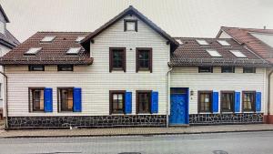 a white house with blue doors and windows at Ferienwohnung sentio-comfortable Saalfeld in Saalfeld