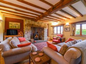 a living room with couches and a stone fireplace at Hope Cottage in Ashreigney