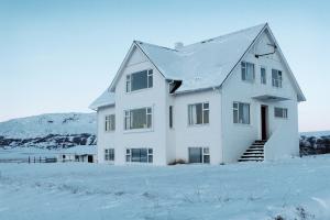 a white house in the snow with a mountain at Mengi Countryside in Kjarnholt