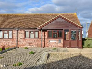 a brick house with a brown door and a driveway at Turnstones in Walcott