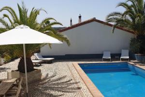 una piscina con sombrilla blanca y sillas en Quinta Do Grilo, en Amoreiras