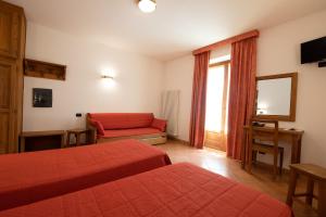 a hotel room with two beds and a red couch at Hotel Casalpina Don Barra in Pragelato