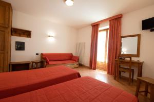 een hotelkamer met 2 bedden en een rode bank bij Hotel Casalpina Don Barra in Pragelato