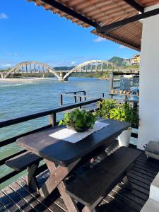 a picnic table with a view of a river and a bridge at Casa Marambaia 2 in Rio de Janeiro