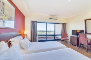 a hotel room with two beds and a television at Yellow Praia Monte Gordo in Monte Gordo