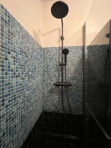 y baño con ducha de azulejos azules. en Perpignan Vauban magnifique T2 avec balcon en Perpiñán