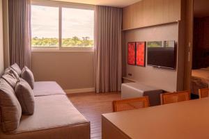 una camera d'albergo con divano, letto e TV di MY MABU a Foz do Iguaçu