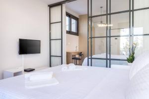 1 dormitorio con 1 cama blanca grande y TV en Central chic flat with terrace btw Syntagma & Monastiraki en Athens