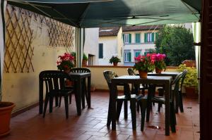 un patio con mesas y sillas bajo una sombrilla verde en L'Acchiappasogni, en Florencia