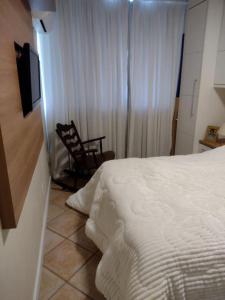 1 dormitorio con 1 cama y 1 silla junto a una ventana en Apto acolhedor perto do Shopping Beira Mar, en Florianópolis