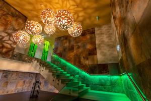 una escalera en un edificio con luz verde y lámparas de araña en Allure Healthy Hotel & Spa, en Eger