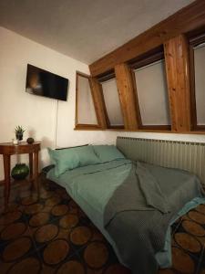 a bedroom with a bed and a table and windows at Emma’s Tiny House in Pila