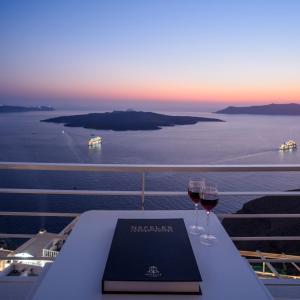 einen Tisch mit zwei Gläsern Wein auf einem Kreuzfahrtschiff in der Unterkunft Nefeles Luxury Suites in Fira