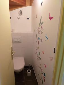 La salle de bains est pourvue de toilettes et de papillons sur le mur. dans l'établissement Duplex de la Croix Paqueray avec vue mer - Chez Hélène - Gîtes en baie, à Carolles