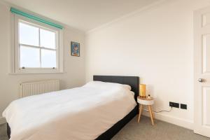 a bedroom with a large white bed and a window at Newly Renovated Central Modern Apartment in Brighton & Hove