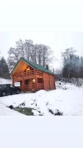 domek z bali na śniegu z samochodem w obiekcie Vikendica MM Kolasin w mieście Kolašin