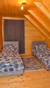 dwa łóżka w pokoju w drewnianym domku w obiekcie Vikendica MM Kolasin w mieście Kolašin