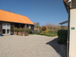 ein Haus mit einem orangenen Dach und einer Kieseinfahrt in der Unterkunft La petite enseigne - Chez Hélène - Gîtes en baie in Champeaux