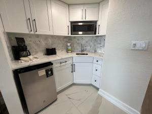 a small kitchen with white cabinets and a microwave at 5 minutes away from Disney, Westgate Resort in Orlando
