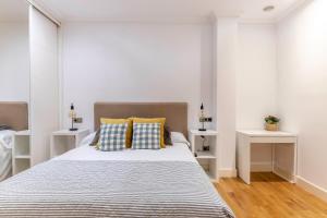 a white bedroom with a large bed with two tables at Azkuna Comfort Bilbao in Bilbao