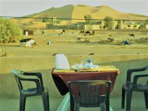 a table and chairs with a view of a desert at Hostel Merzouga Tifinagh in Merzouga
