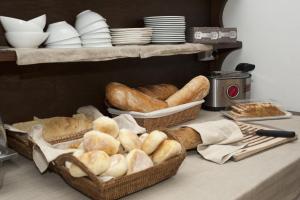 two baskets filled with bread on a counter with plates at Nascar Hotel in Santa Maria Navarrese