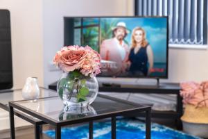 a vase with a flower on a table in front of a tv at Spacious 2 bed house with free on street parking in Birmingham