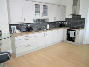 uma cozinha com armários brancos e piso em madeira em Firpoint em Rockcliffe