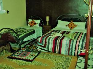 a bedroom with two beds and a rug at Hostel Merzouga Tifinagh in Merzouga