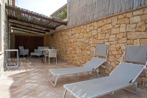 a patio with chairs and tables and a stone wall at Nascar Hotel in Santa Maria Navarrese