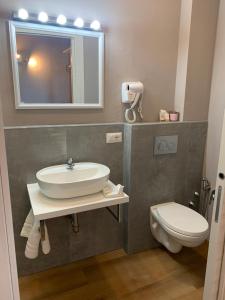 ein Badezimmer mit einem Waschbecken, einem WC und einem Spiegel in der Unterkunft Piccola Dimora B&B in Lucca