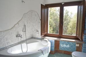 a bath tub in a bathroom with a window at Nascar Hotel in Santa Maria Navarrese