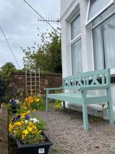 eine blaue Bank vor einem Fenster mit Blumen in der Unterkunft St John's Flat Spacious Accomodation in Dalry